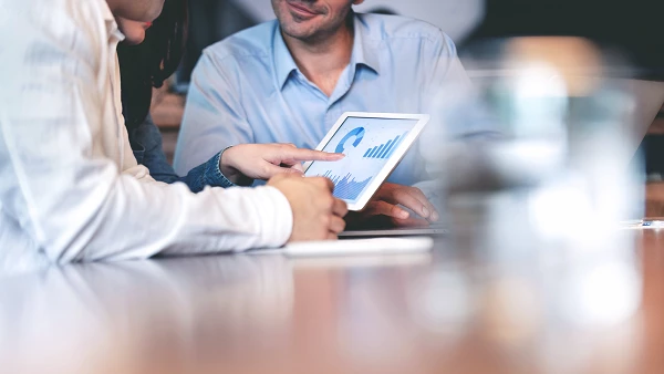 Team betrachtet Tablet mit Diagrammen und Statistiken
