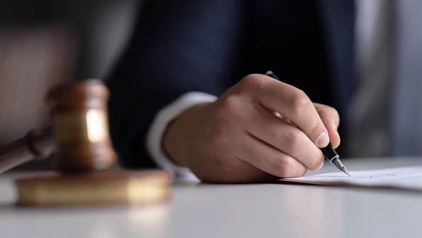 Juristische Szene mit Hand, Stift und Richterhammer