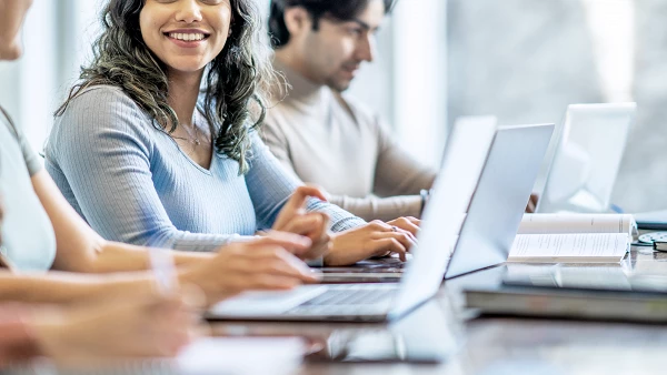 Junge Berufstätige arbeiten gemeinsam an Laptops