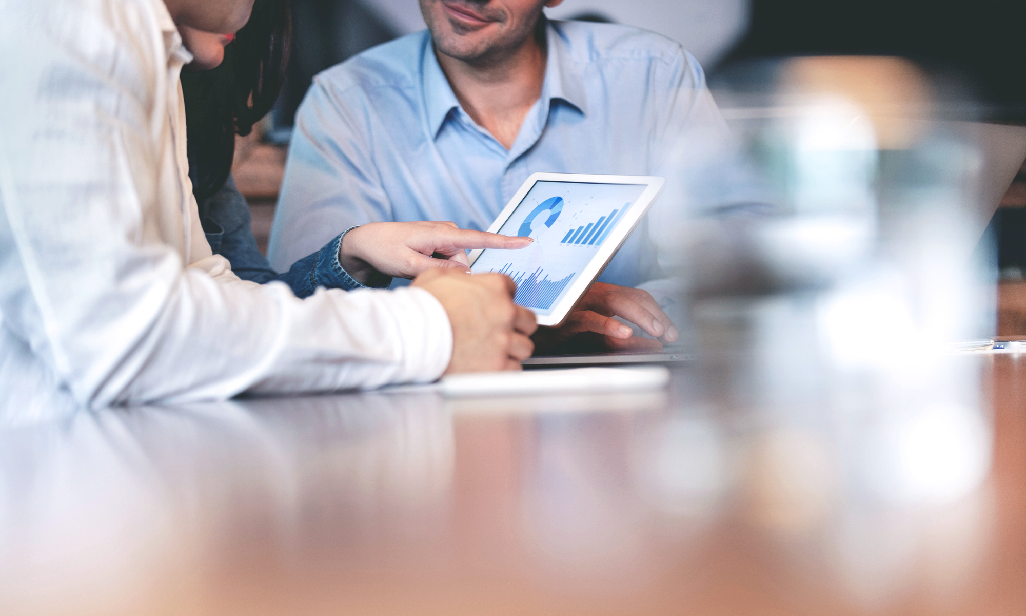 Team betrachtet Tablet mit Diagrammen und Statistiken