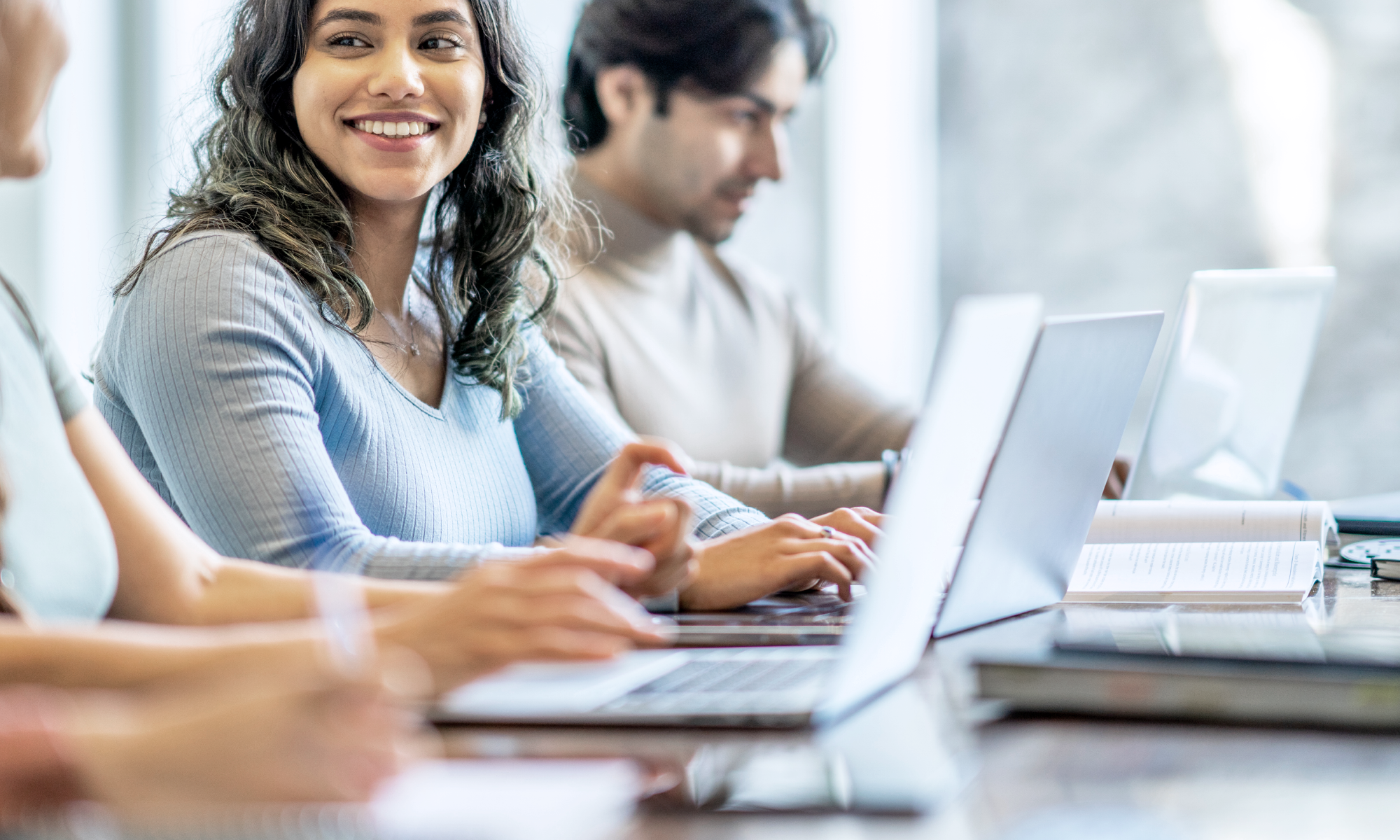 Junge Berufstätige arbeiten gemeinsam an Laptops